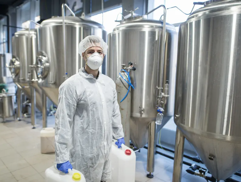 A man in a protective suit standing in front of a brewery